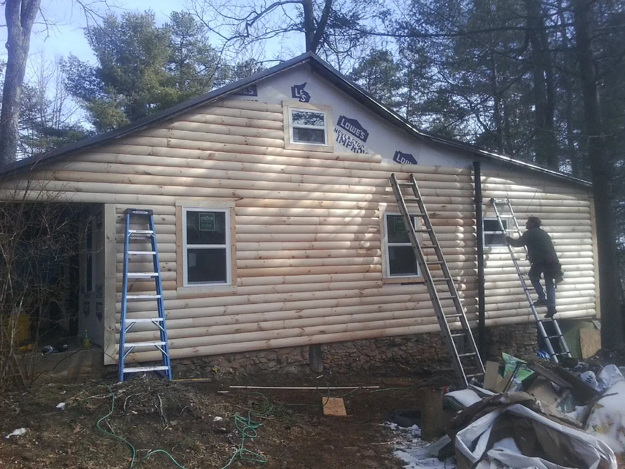Ladders set against fresh log siding during an exterior remodel in Swisher