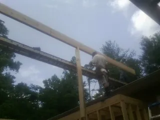 Carpenter setting a ridge beam over a new addition frame — Ice Dam Removal by Roofing Brothers in Swisher