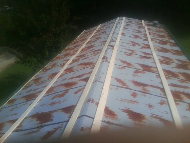 Rusted metal roof panels with new wood purlins before replacement — Storm Damage Roof Repair in Swisher by Roofing Brothers