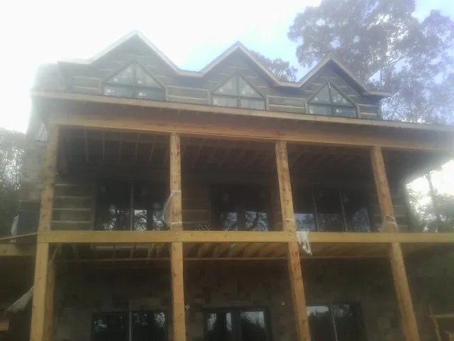 Dormers and porch framing on a large log home under construction — Roof Coating work by our crew in Swisher