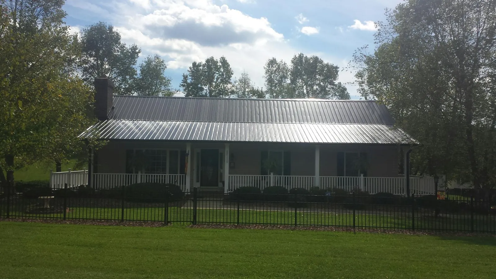 Gray metal roof on a brick ranch with a full width front porch — Gutter Guard Installation work by our crew in Swisher