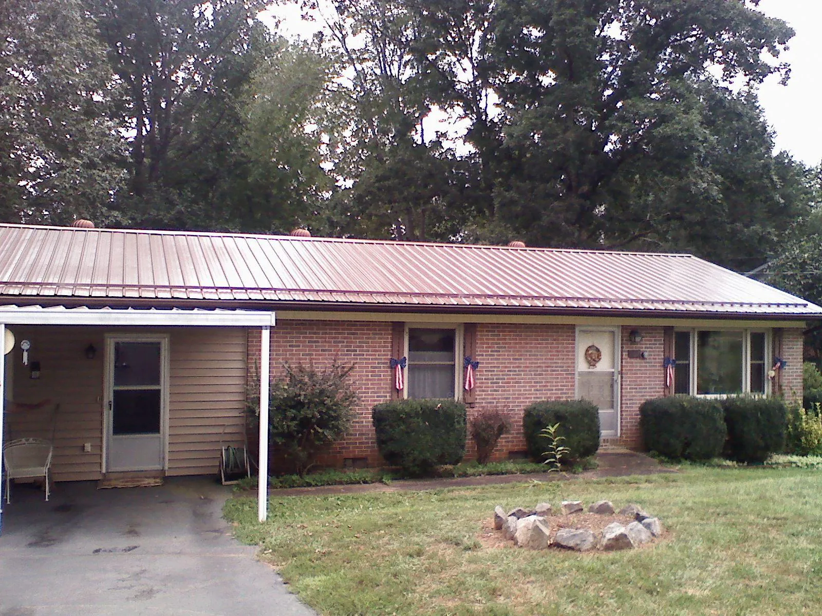 Bronze metal roof and carport on a brick ranch home — Roof Repair work by our crew in Swisher