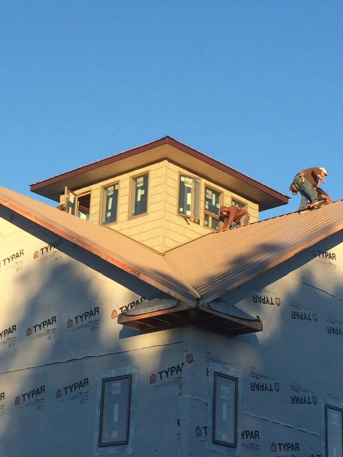 Roofers working around a rooftop cupola on a new metal roof at sunset — Roof Waterproofing in Swisher by Roofing Brothers